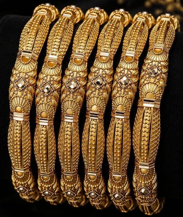 Set of six gold bangles with intricate relief patterning and geometric diamond shapes