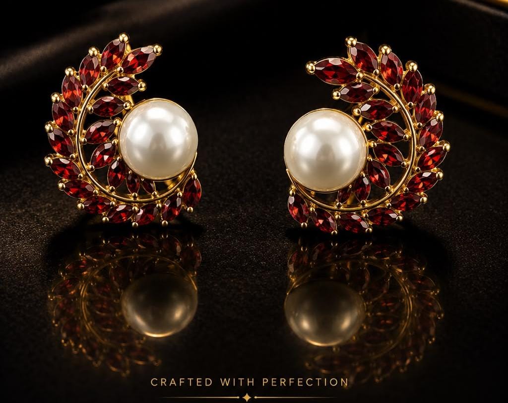Crescent-shaped earrings set with red garnets hugging a white pearl